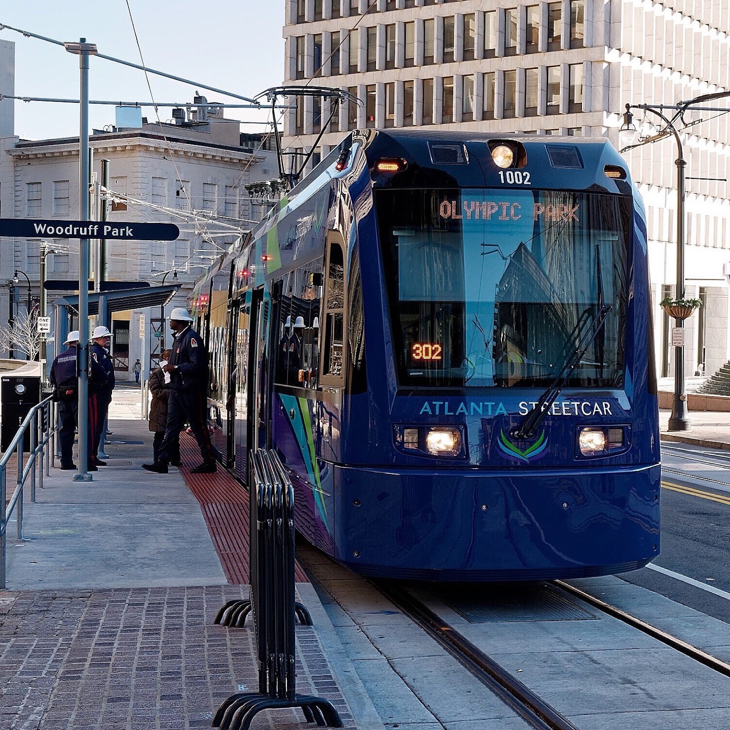 A blue Atlanta Streetcar seen from the front, with overhead wires above it